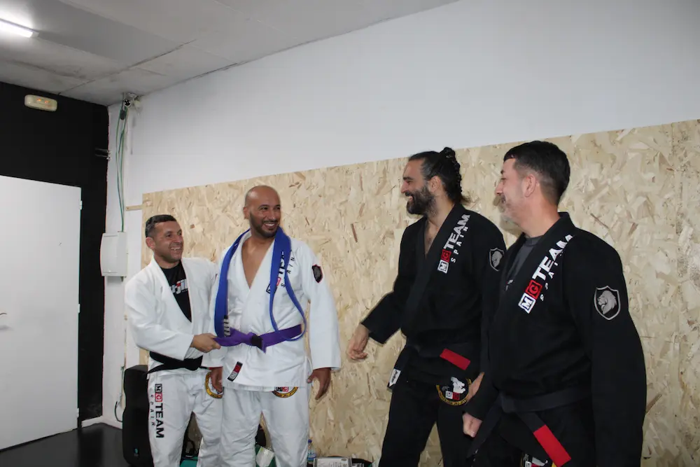 Alumnos de Jiu-Jitsu Brasileño celebrando un ascenso de cinturón durante una clase en la academia